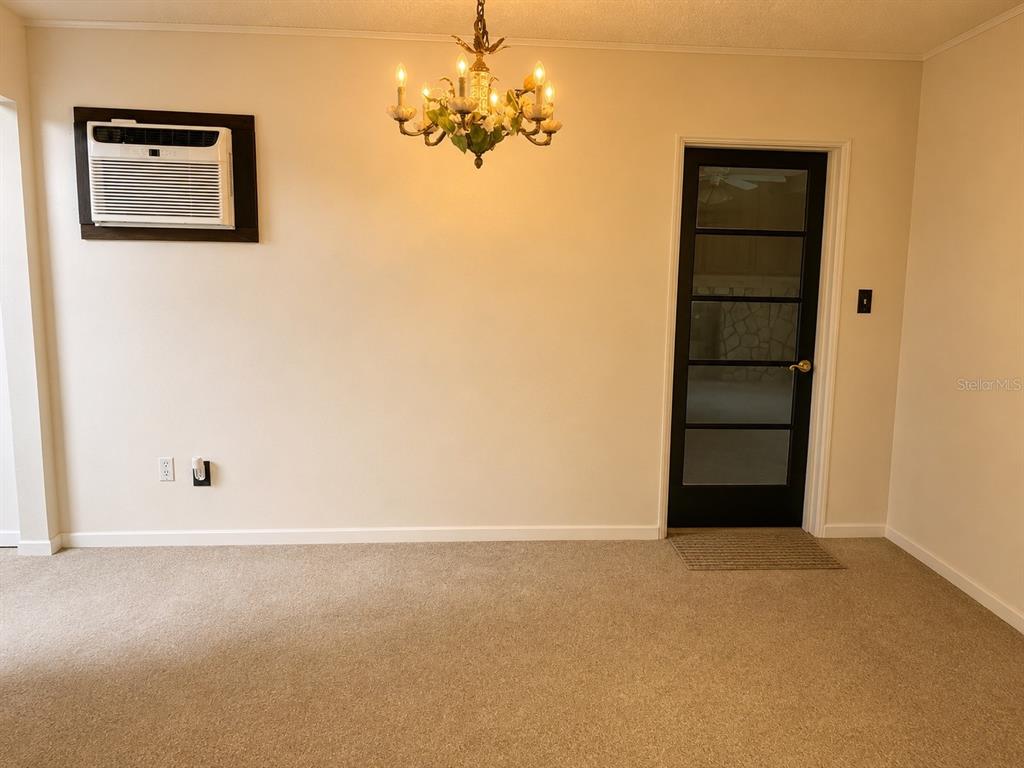 A dining room with beige carpet, a floral chandelier, a wall-mounted air conditioner, and a door — 315 LAKE SEMINARY CIRCLE, MAITLAND, FL