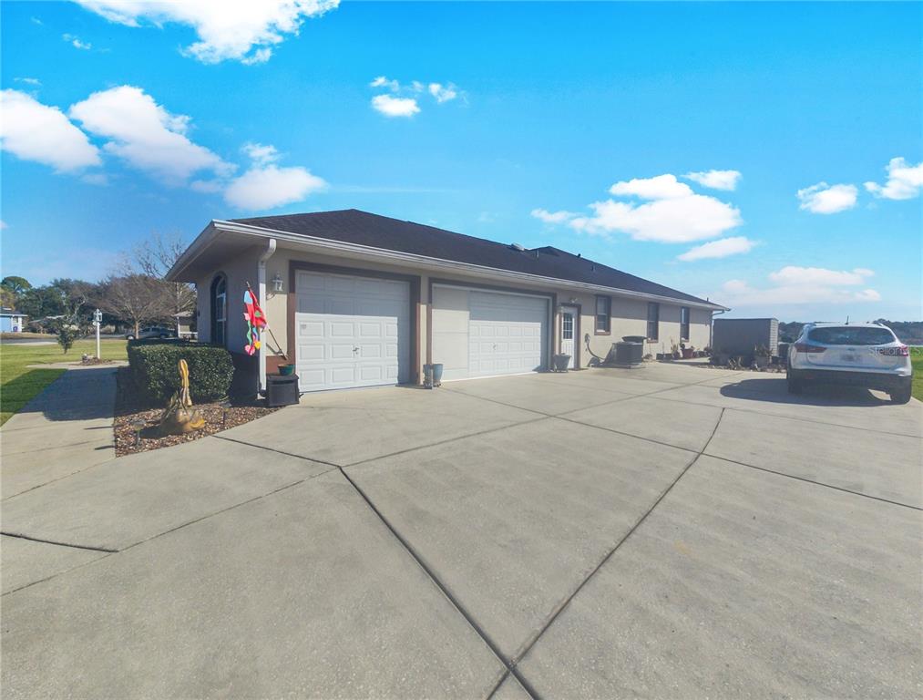 A single-story house with a two-car garage and a concrete driveway under a blue sky — 77 HICKORY LOOP, OCALA, FL
