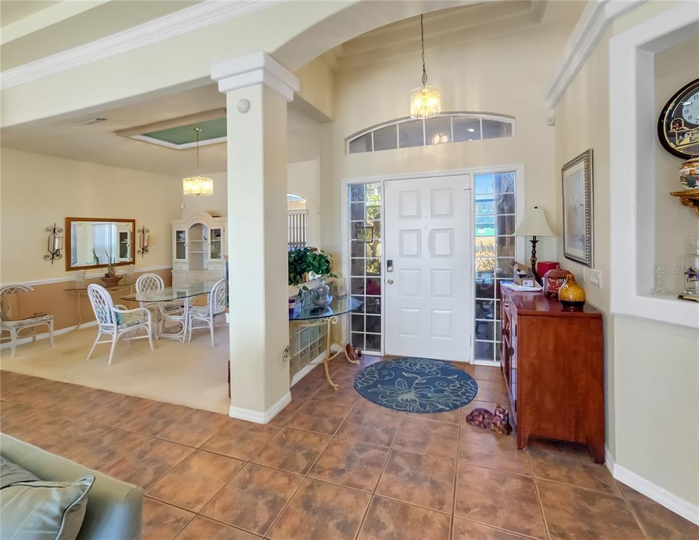 An entryway with tile flooring leads to a dining area with carpet and white furniture — 77 HICKORY LOOP, OCALA, FL