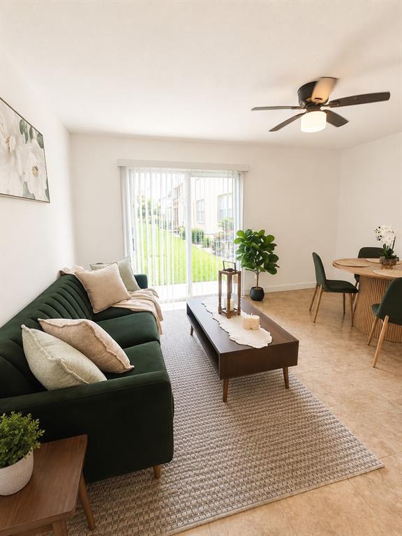 An open-concept living and dining area features a round wooden table and a green sofa — 5820 N CHURCH AVENUE UNIT 112, TAMPA, FL