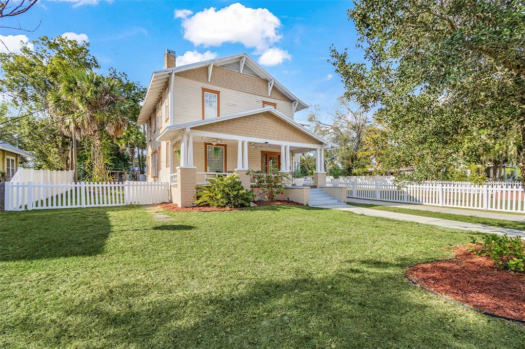 A two-story house with a front porch, tan siding, and a white picket fence — 213 N MONROE AVENUE, ARCADIA, FL