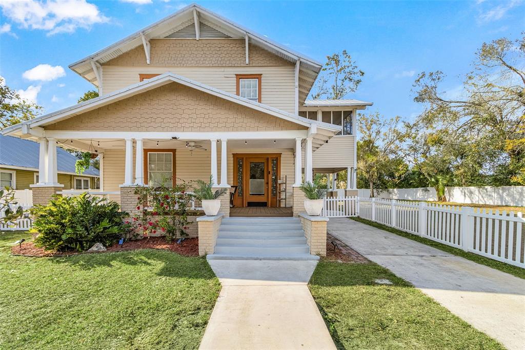 A two-story house with a front porch, tan siding, and a white picket fence — 213 N MONROE AVENUE, ARCADIA, FL