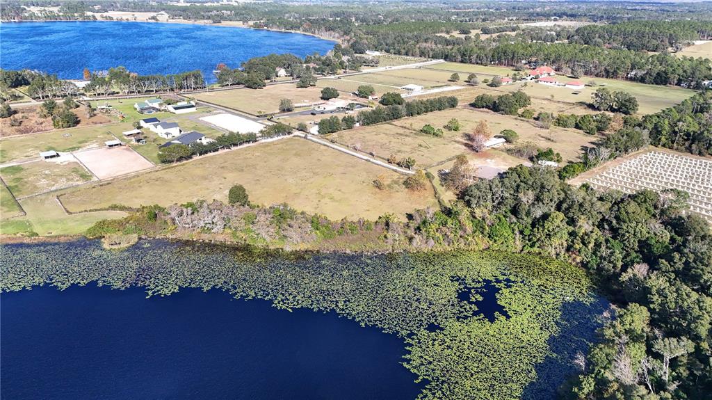 An aerial view shows a grassy field bordering a lake covered in lily pads — 000 KENNY TRAIL, EUSTIS, FL