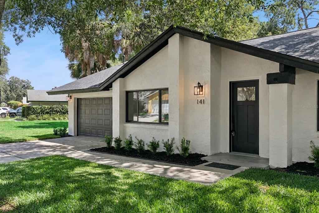 A white house with a dark roof, black trim, a garage, and a front entry door — 141 MILL RUN DRIVE, LAKE MARY, FL