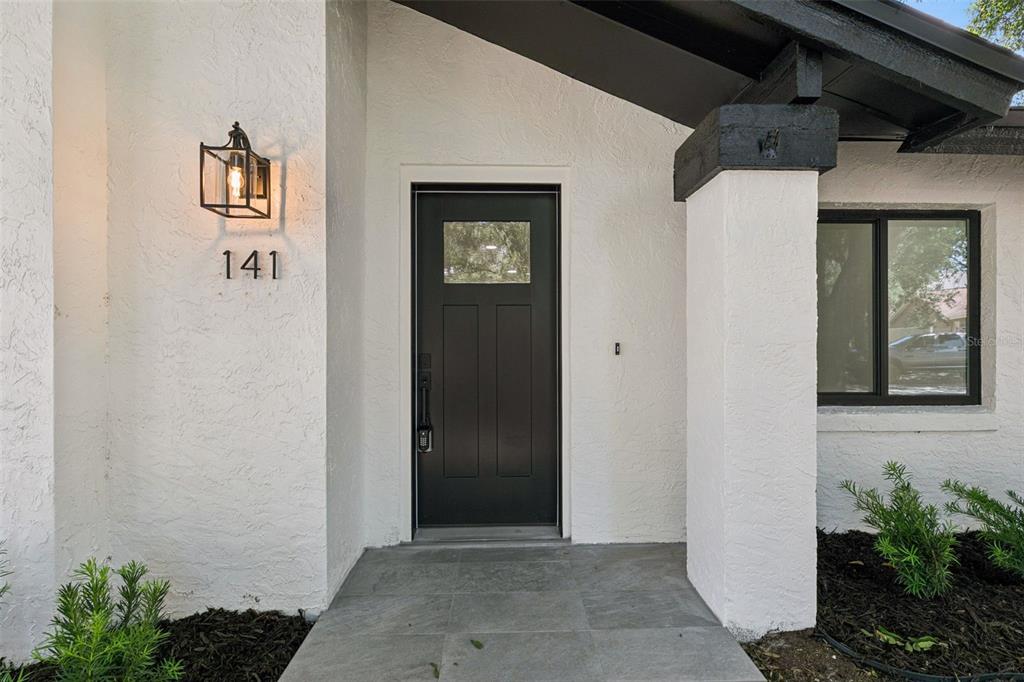The exterior entrance features a black door, white stucco walls, and a gray tiled porch — 141 MILL RUN DRIVE, LAKE MARY, FL