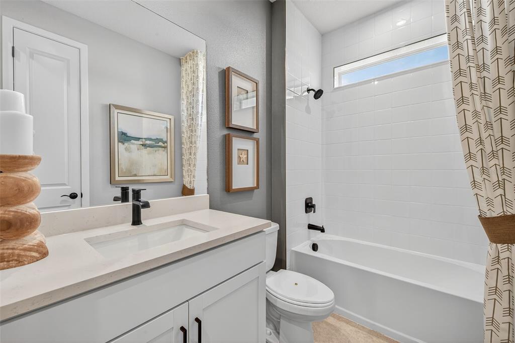 A bathroom features a white vanity, a tub-shower combination with white tile, and patterned curtains — 35504 PEAK WILLOW TRACE, DADE CITY, FL