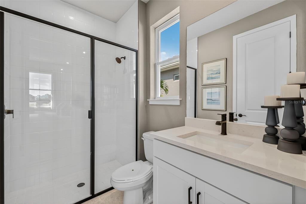 A bathroom features a white vanity, a glass-enclosed shower, a toilet, and a window — 35504 PEAK WILLOW TRACE, DADE CITY, FL