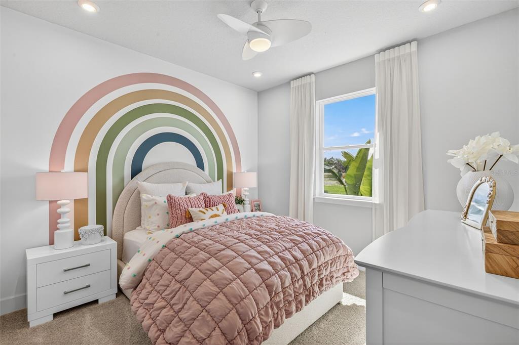 A bedroom features a rainbow wall mural, a pink quilted bed, and white furniture — 35504 PEAK WILLOW TRACE, DADE CITY, FL