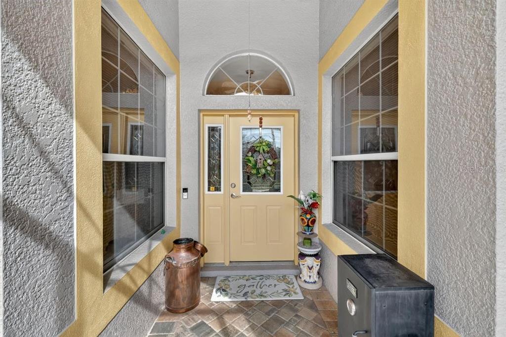 A front entryway features a yellow door, arched transom window, and tiled floor — 3606 MULBERRY GROVE LOOP, LEESBURG, FL