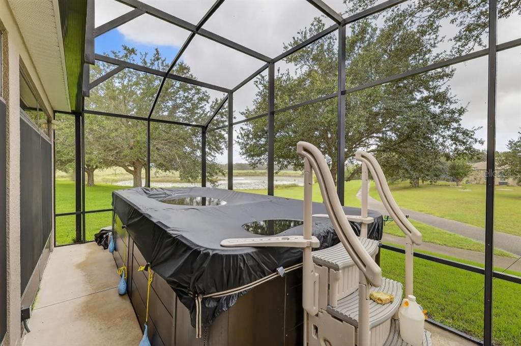 A screened-in patio features a covered hot tub with steps and a view of grass — 3606 MULBERRY GROVE LOOP, LEESBURG, FL