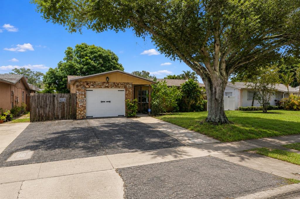 A single-story house with a stone-faced garage, a paved driveway, and a large shade tree — 2051 23RD STREET SW, LARGO, FL