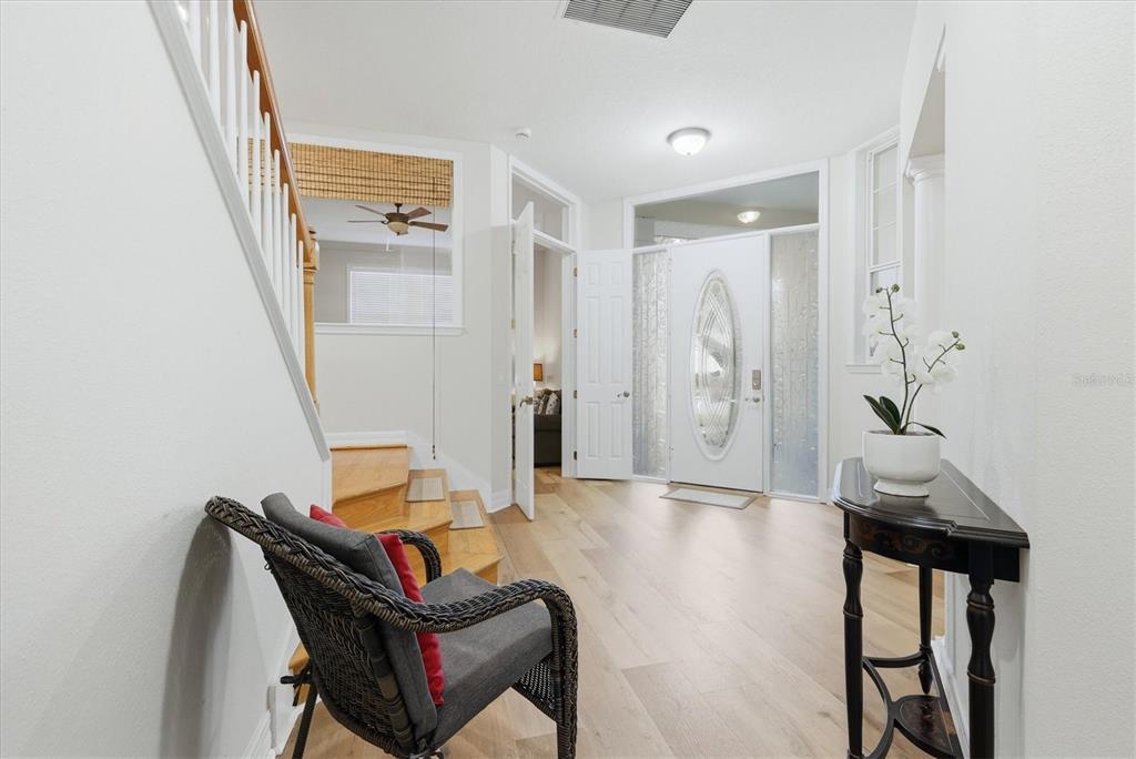 An entryway features light wood flooring, a white front door with glass, and a staircase — 3409 54TH DRIVE W UNIT 103, BRADENTON, FL
