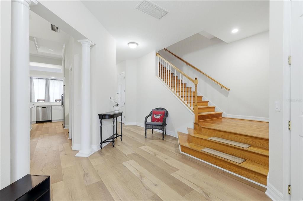 An entryway features light wood flooring, a staircase with wooden steps, and white columns — 3409 54TH DRIVE W UNIT 103, BRADENTON, FL
