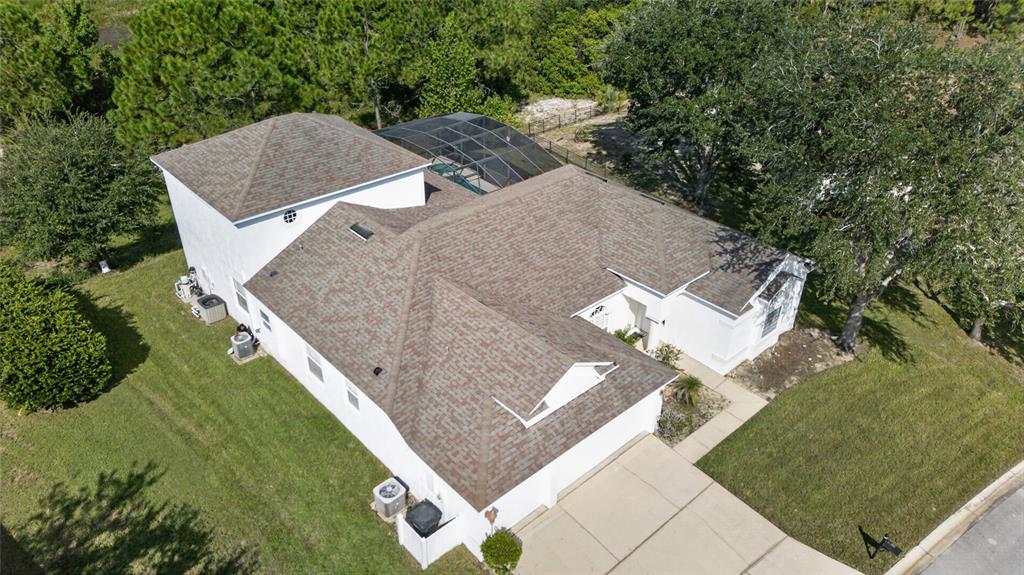 An aerial view of a white house with a brown shingled roof and pool enclosure — 219 BLUE HERON COURT, DAVENPORT, FL