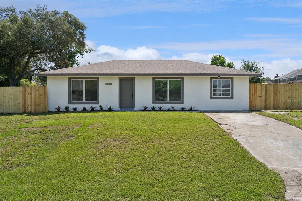 A single-story house with a light-colored exterior, a concrete driveway, and a wooden fence — 2715 TIMBERLAKE AVENUE, DELTONA, FL