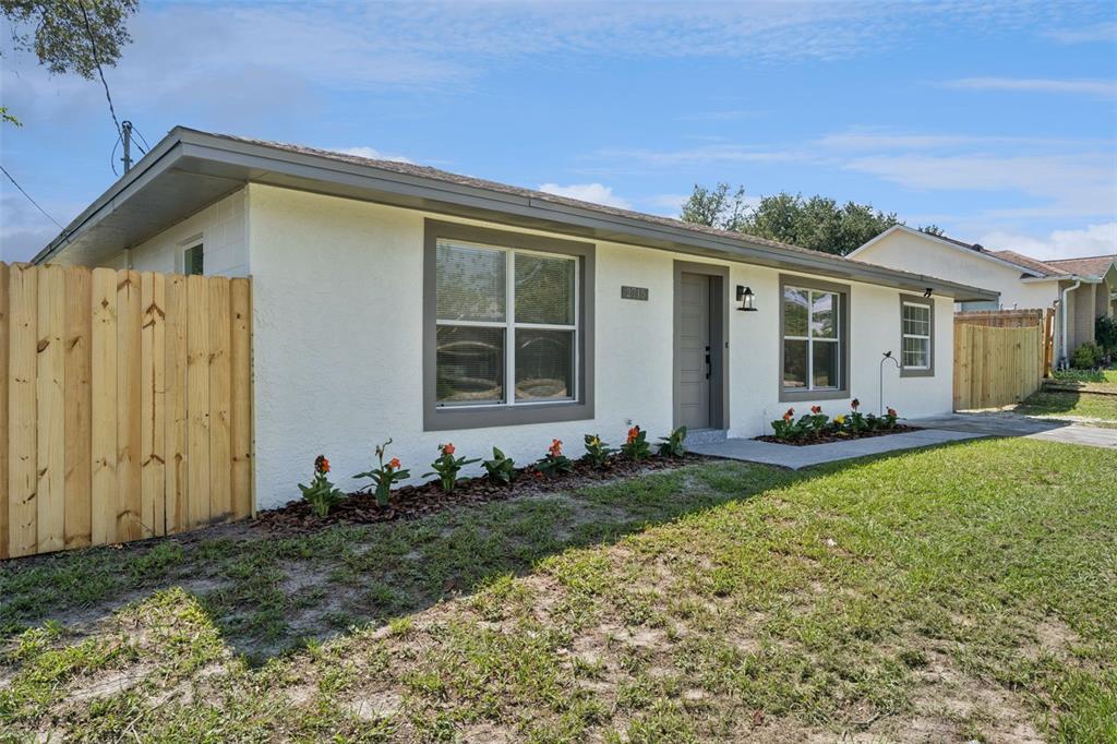 A single-story house with a white stucco exterior, grey trim, and a wooden privacy fence — 2715 TIMBERLAKE AVENUE, DELTONA, FL