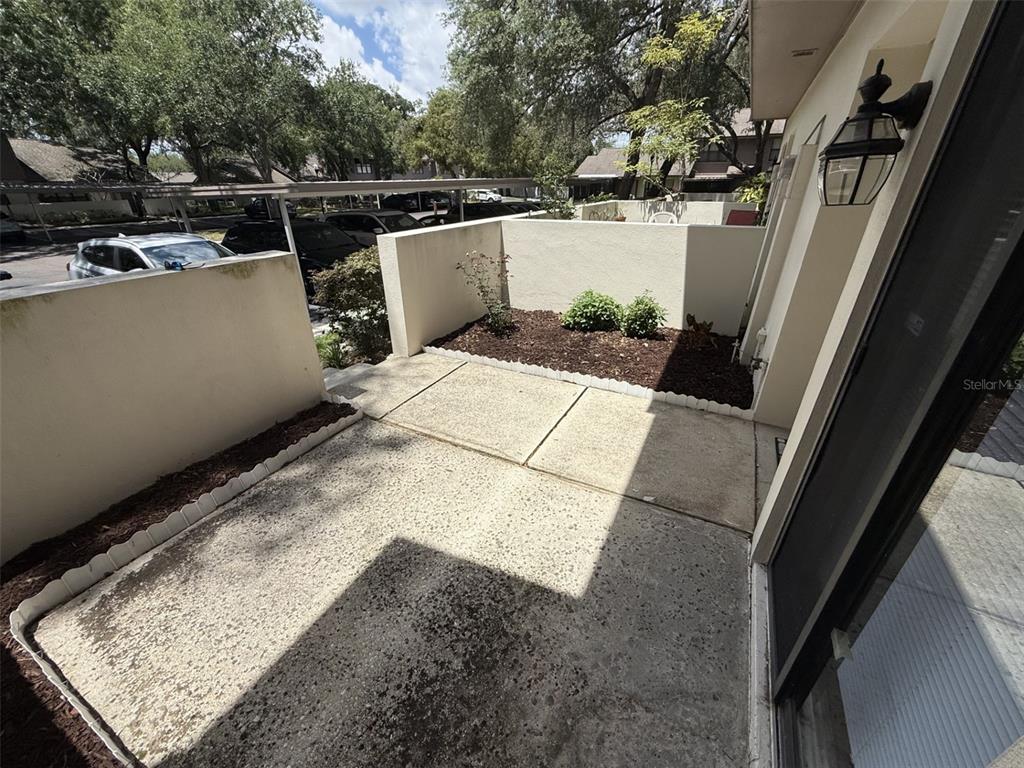 A concrete patio features a small garden bed enclosed by low stucco walls — 819 OAK PARK PLACE, BRANDON, FL
