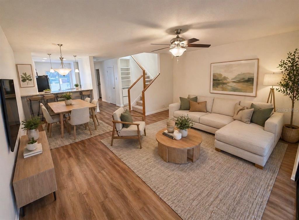 An open-concept living and dining area features light wood flooring, a sectional sofa, and stairs — 819 OAK PARK PLACE, BRANDON, FL
