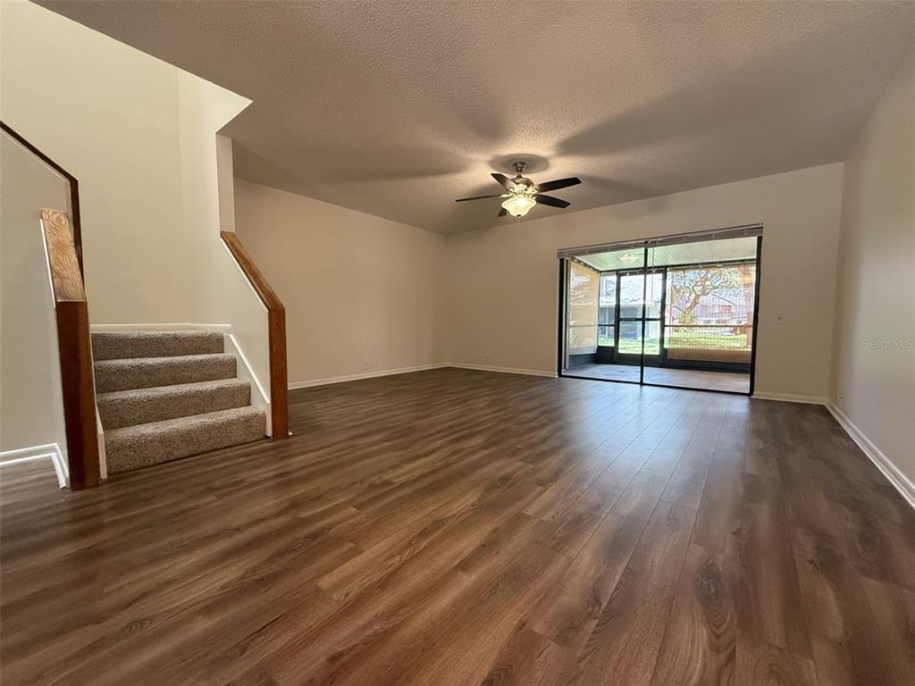 A living room features wood-look flooring, a carpeted staircase, and sliding glass doors to a patio — 819 OAK PARK PLACE, BRANDON, FL