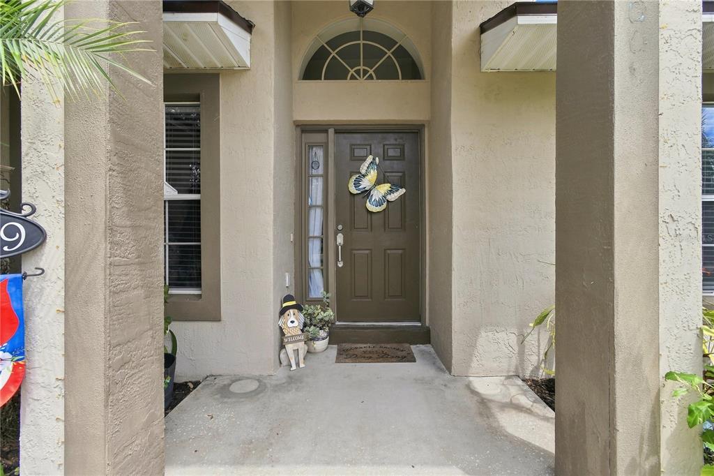 A front entryway features a brown door with a butterfly decoration and a dog statue — 1009 SPRING LOOP WAY, WINTER GARDEN, FL