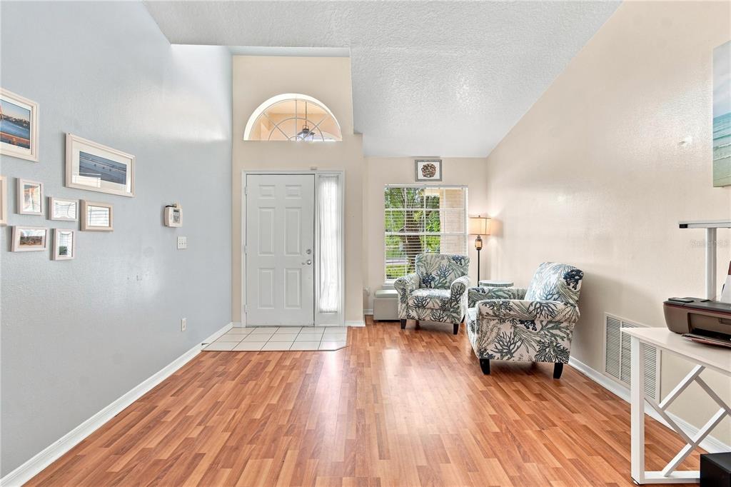 A living room features wood-look flooring, two patterned armchairs, and a white front door — 1009 SPRING LOOP WAY, WINTER GARDEN, FL