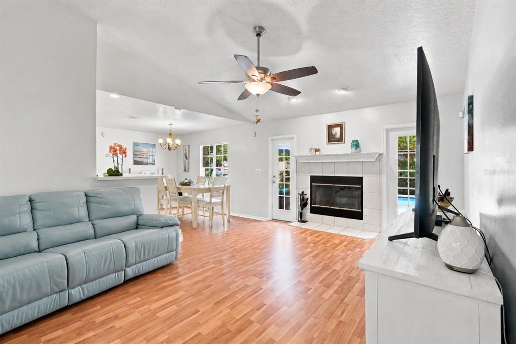 A living room with a light blue sofa, fireplace, dining area, and wood-look flooring — 1009 SPRING LOOP WAY, WINTER GARDEN, FL