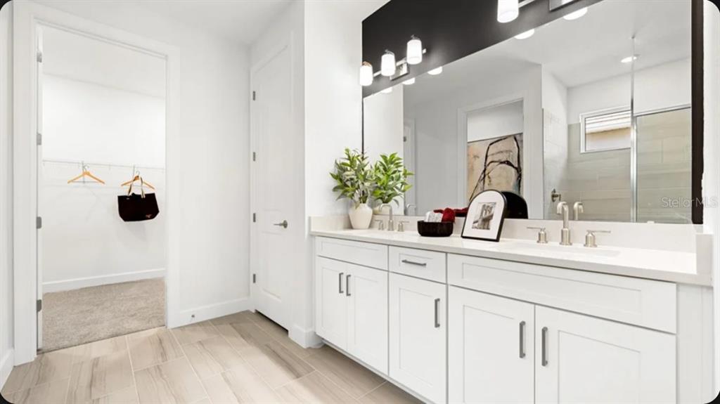 A modern open-concept kitchen features white cabinetry, a large marble-topped island, and light wood flooring — 7424 MOONBEAM AVENUE, SARASOTA, FL