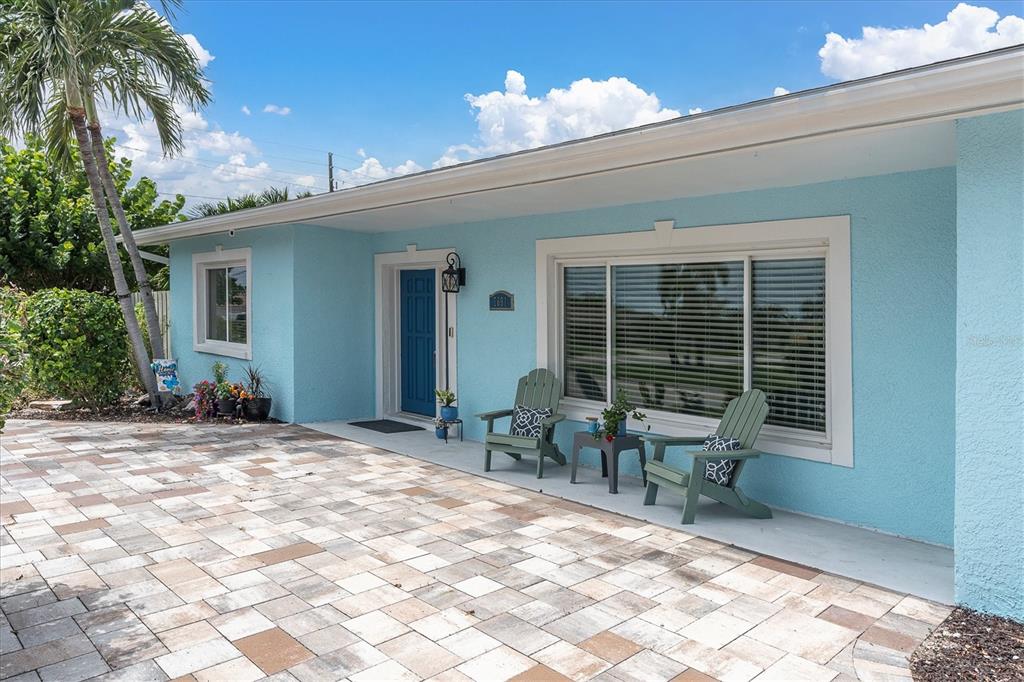 A light blue house exterior features a paved driveway, a front porch, and two green chairs — 7891 4TH AVENUE S, ST PETERSBURG, FL