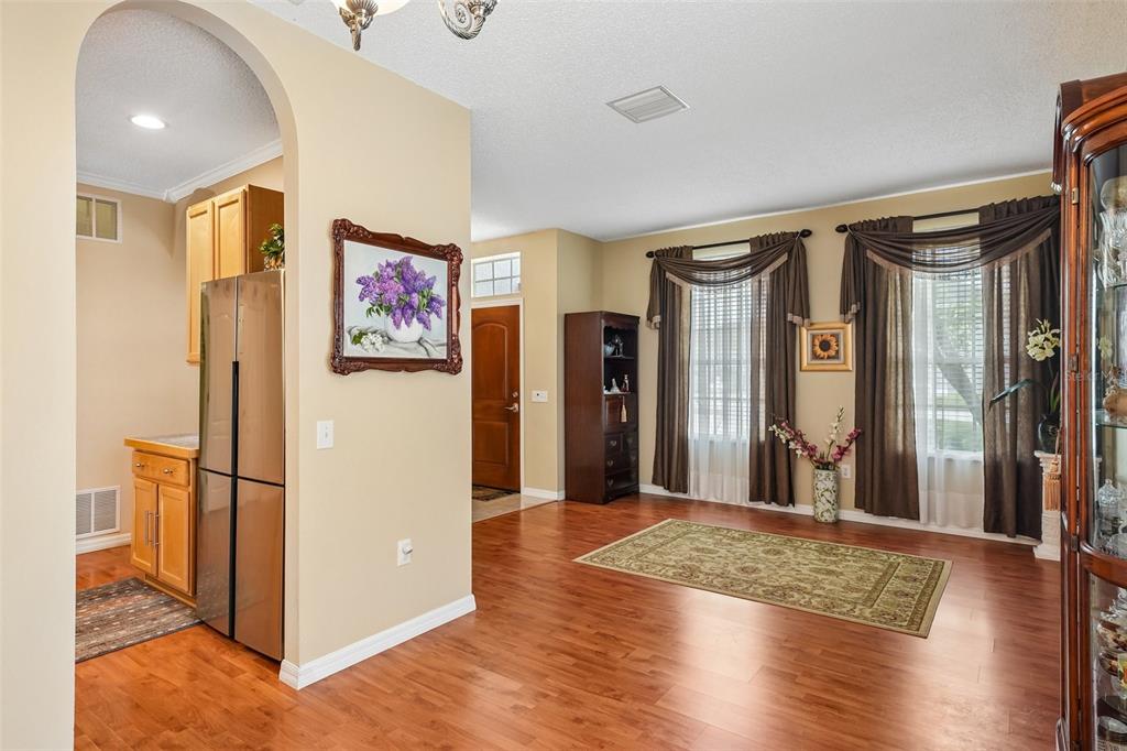 A dining area with hardwood floors, a rug, and an arched entryway to the kitchen — 4236 TARKINGTON DRIVE, LAND O LAKES, FL