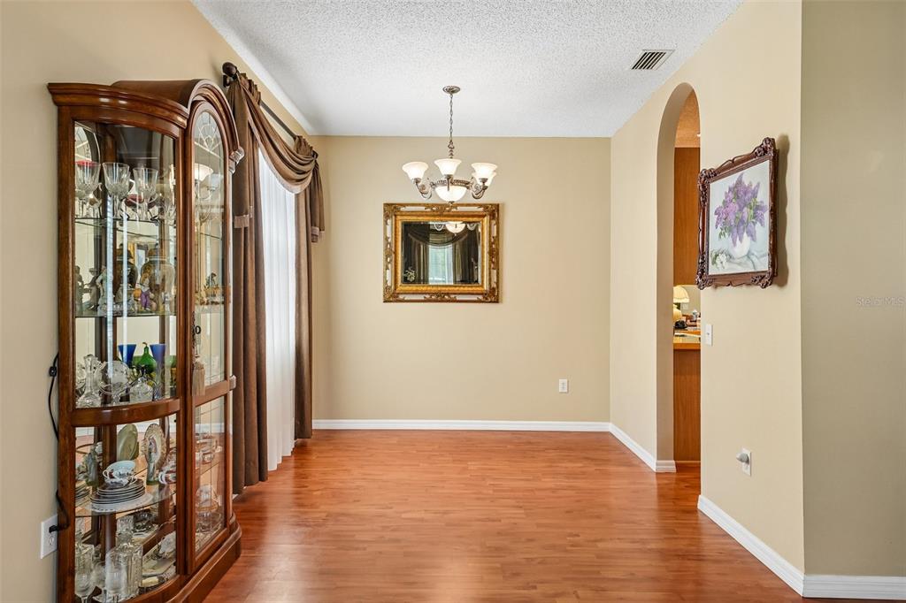A dining room with wood flooring, a glass display cabinet, and a chandelier — 4236 TARKINGTON DRIVE, LAND O LAKES, FL