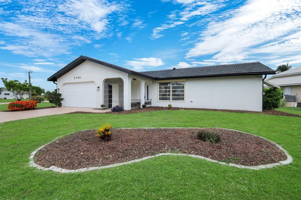 A single-story white house with a tiled roof, a two-car garage, and a landscaped yard — 2700 W MARION AVENUE, PUNTA GORDA, FL