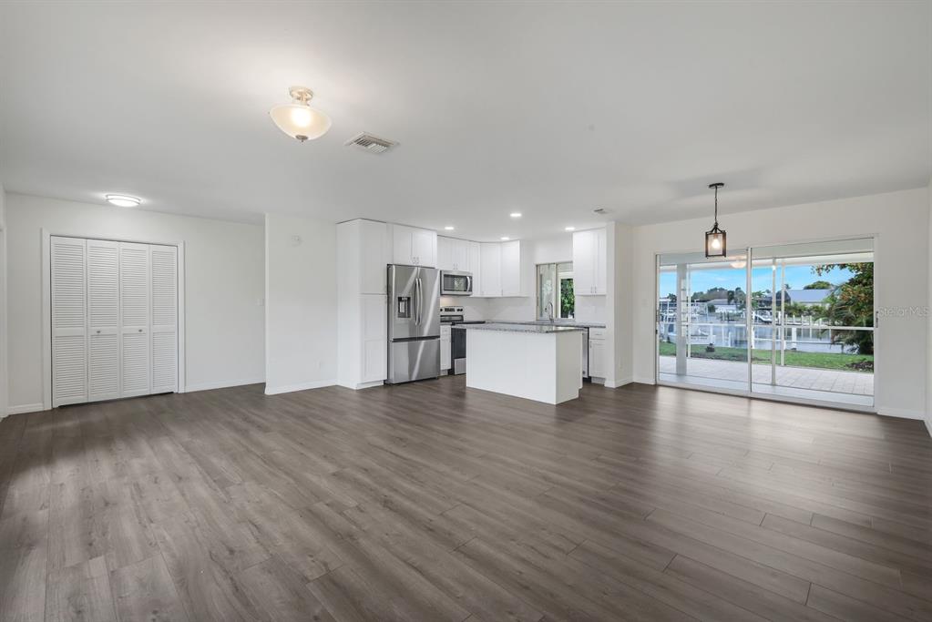 An open-concept kitchen and living area features white cabinetry, stainless steel appliances, and wood flooring — 2700 W MARION AVENUE, PUNTA GORDA, FL