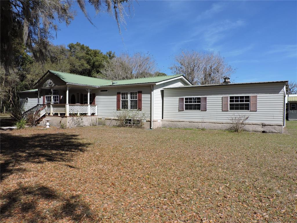 A single-story house with light-colored siding, a green metal roof, and a front porch — 148 DENVER ROAD, CRESCENT CITY, FL