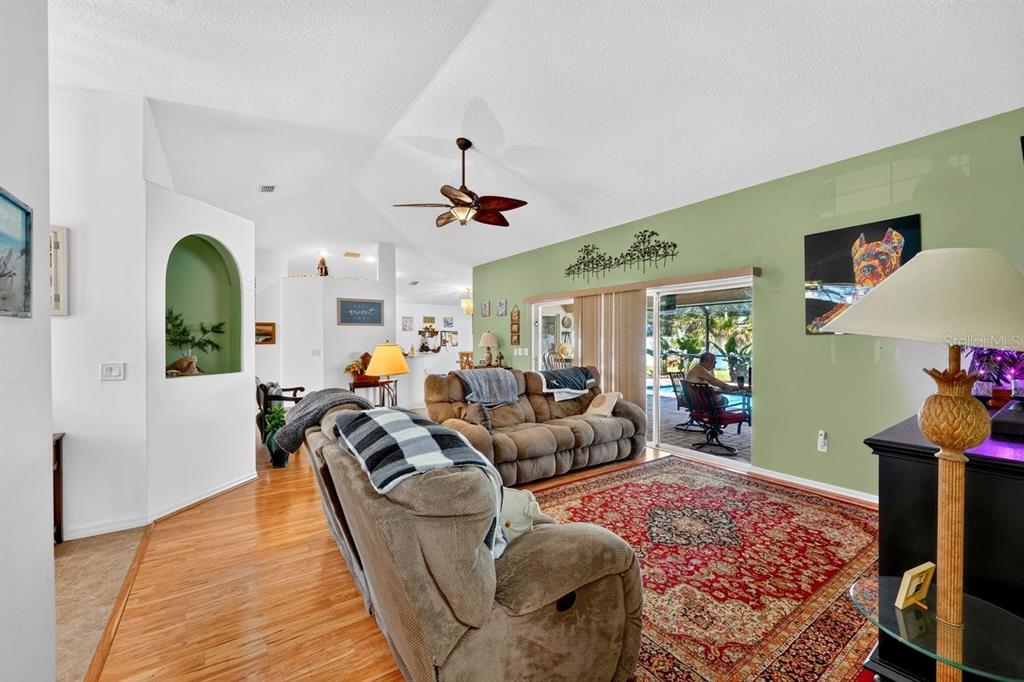 A living room with hardwood floors, a red area rug, and a green accent wall — 15 PINE CEDAR DRIVE, PALM COAST, FL