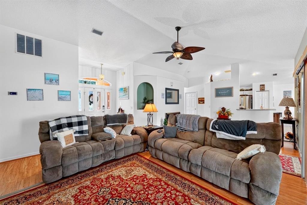 A living room features two brown reclining sofas, a patterned area rug, and vaulted ceilings — 15 PINE CEDAR DRIVE, PALM COAST, FL
