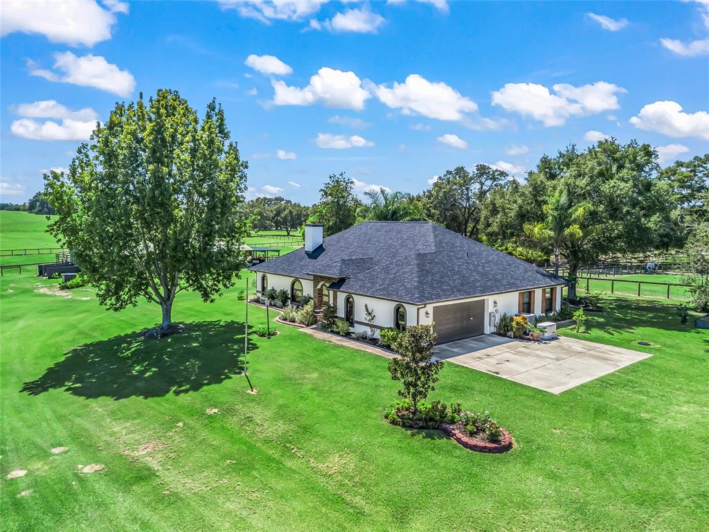 An aerial view shows a single-story white house with a dark roof and large lawn — 15600 SE 47TH AVENUE, SUMMERFIELD, FL