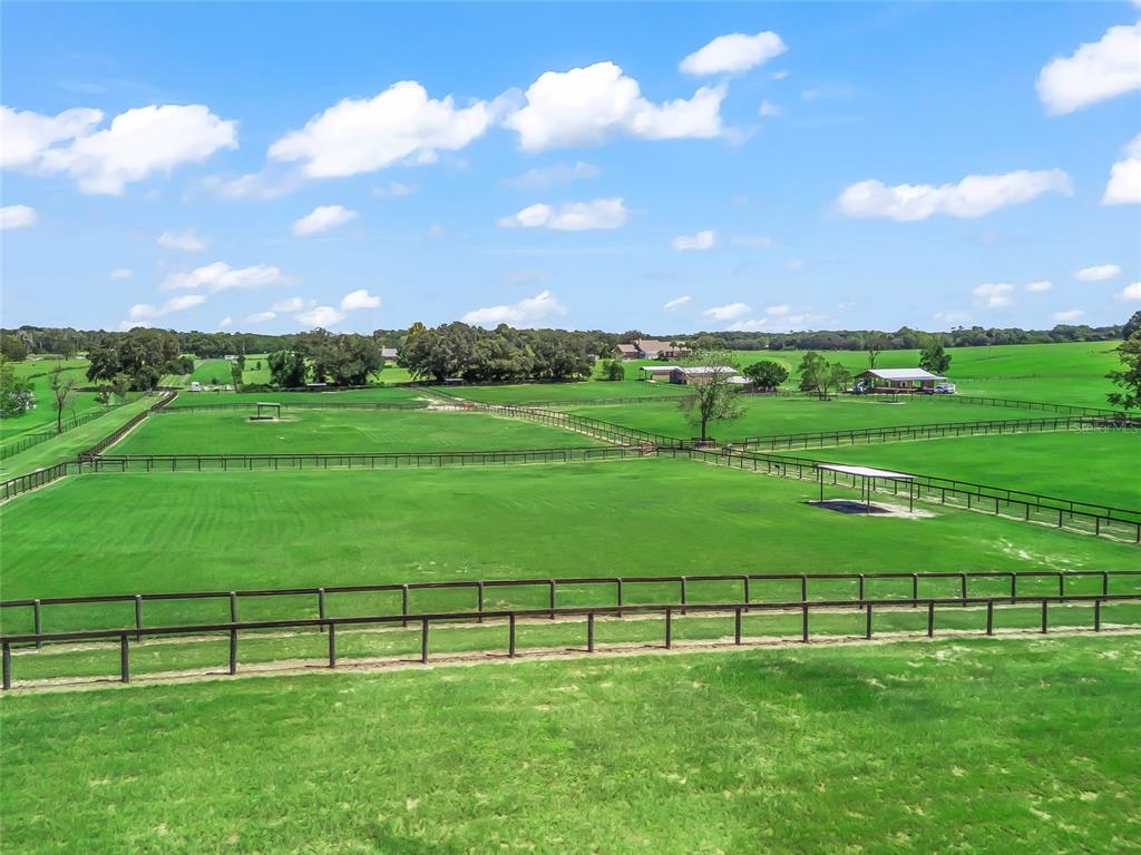 A wide-angle view of a large, fenced green pasture with a small covered shelter — 15600 SE 47TH AVENUE, SUMMERFIELD, FL