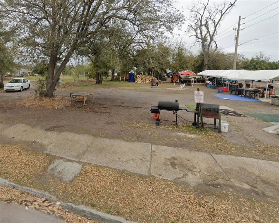 An outdoor lot features a large white canopy, a grill, and scattered trees — 1472 EAVERSON STREET, JACKSONVILLE, FL