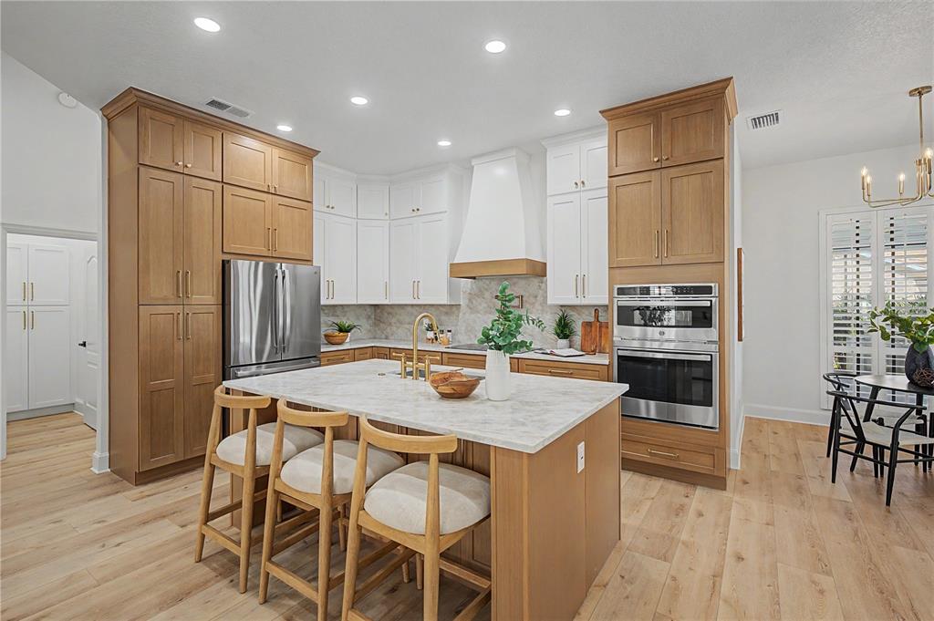 A kitchen features a marble-topped island, two-toned cabinetry, and stainless steel appliances — 35 GREENHAVEN TRAIL, OLDSMAR, FL