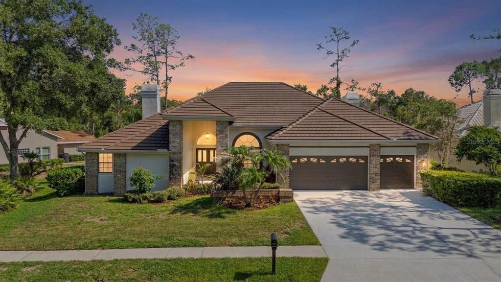 A single-story house with a brown tile roof, stone accents, and a three-car garage — 35 GREENHAVEN TRAIL, OLDSMAR, FL