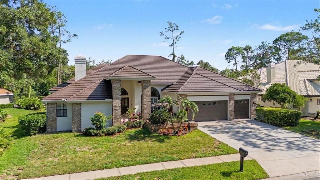 A single-story house with a brown tile roof, stone accents, and a three-car garage — 35 GREENHAVEN TRAIL, OLDSMAR, FL