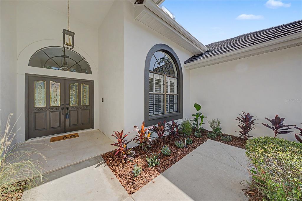 The exterior entrance features a double door, an arched window, and a landscaped garden bed — 35 GREENHAVEN TRAIL, OLDSMAR, FL