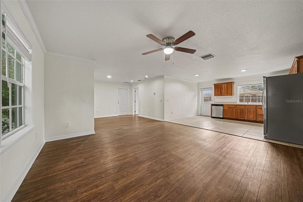A spacious open-concept living area features wood-look flooring and an adjacent kitchen with wooden cabinets — 245 OAK RUN COURT, APOPKA, FL