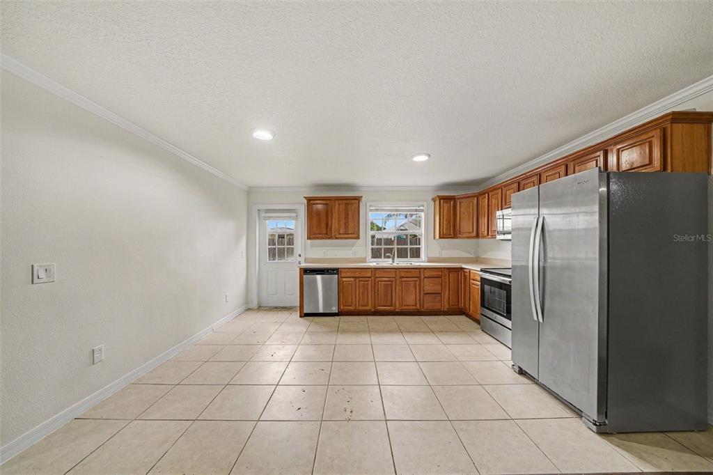 A kitchen with wood cabinets and stainless steel appliances opens into a living area — 245 OAK RUN COURT, APOPKA, FL