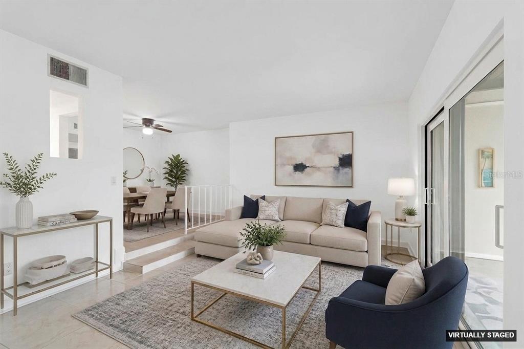A living room with a beige sectional, a navy armchair, and a raised dining area — 552 PLAZA SEVILLE COURT UNIT 97, TREASURE ISLAND, FL