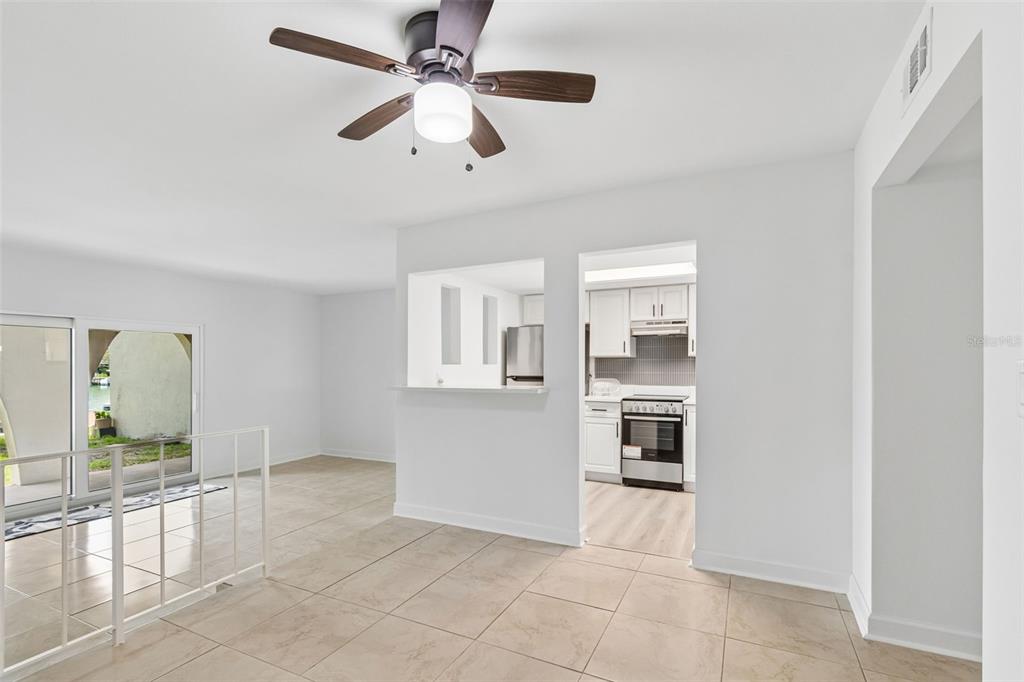 An interior view shows a tiled dining area with a ceiling fan and kitchen pass-through — 552 PLAZA SEVILLE COURT UNIT 97, TREASURE ISLAND, FL