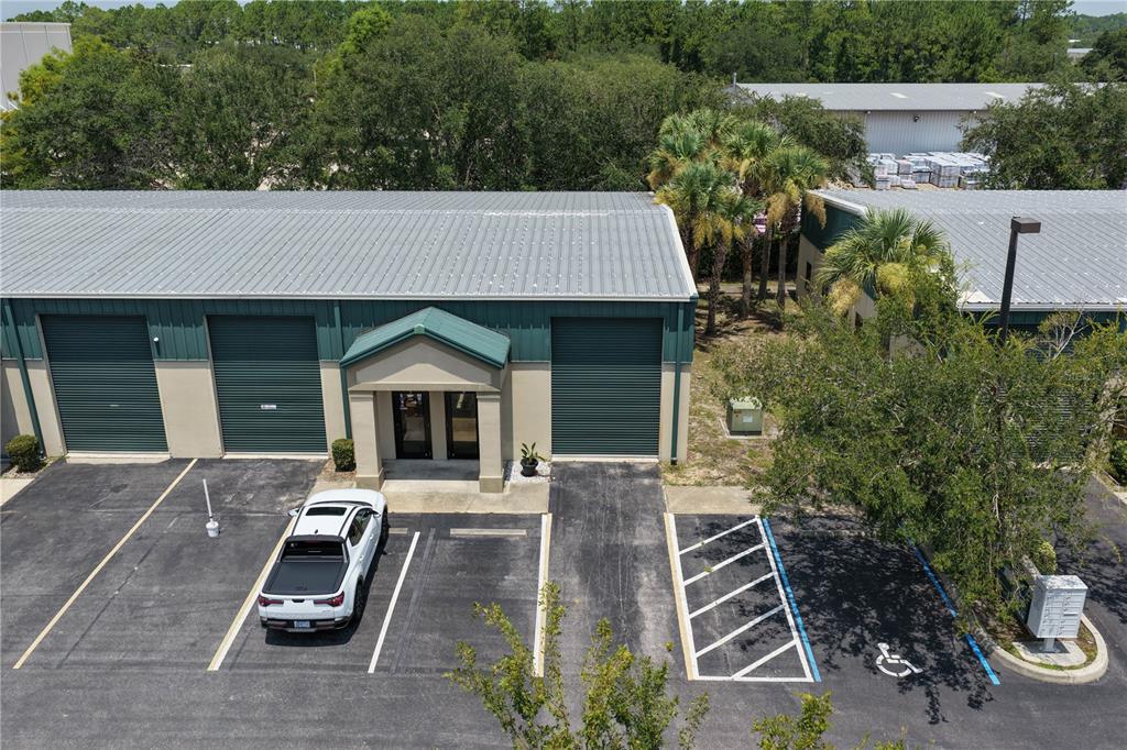 An aerial view shows a commercial building with three roll-up doors and a central entrance — 1291 N US HIGHWAY 1 UNIT 7, ORMOND BEACH, FL