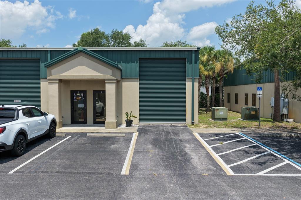 An exterior view of a commercial building with a roll-up door and a parking lot — 1291 N US HIGHWAY 1 UNIT 7, ORMOND BEACH, FL