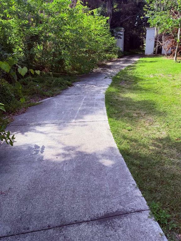 A concrete walkway leads toward two white pillars surrounded by trees and grass — 10984 PARK RIDGE GOTHA ROAD, WINDERMERE, FL