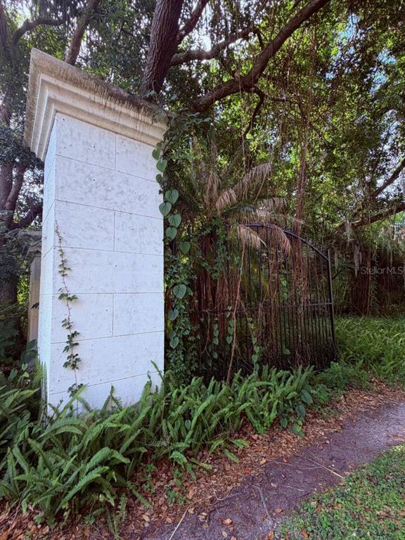 A white stone pillar stands next to a black metal gate surrounded by lush greenery — 10984 PARK RIDGE GOTHA ROAD, WINDERMERE, FL